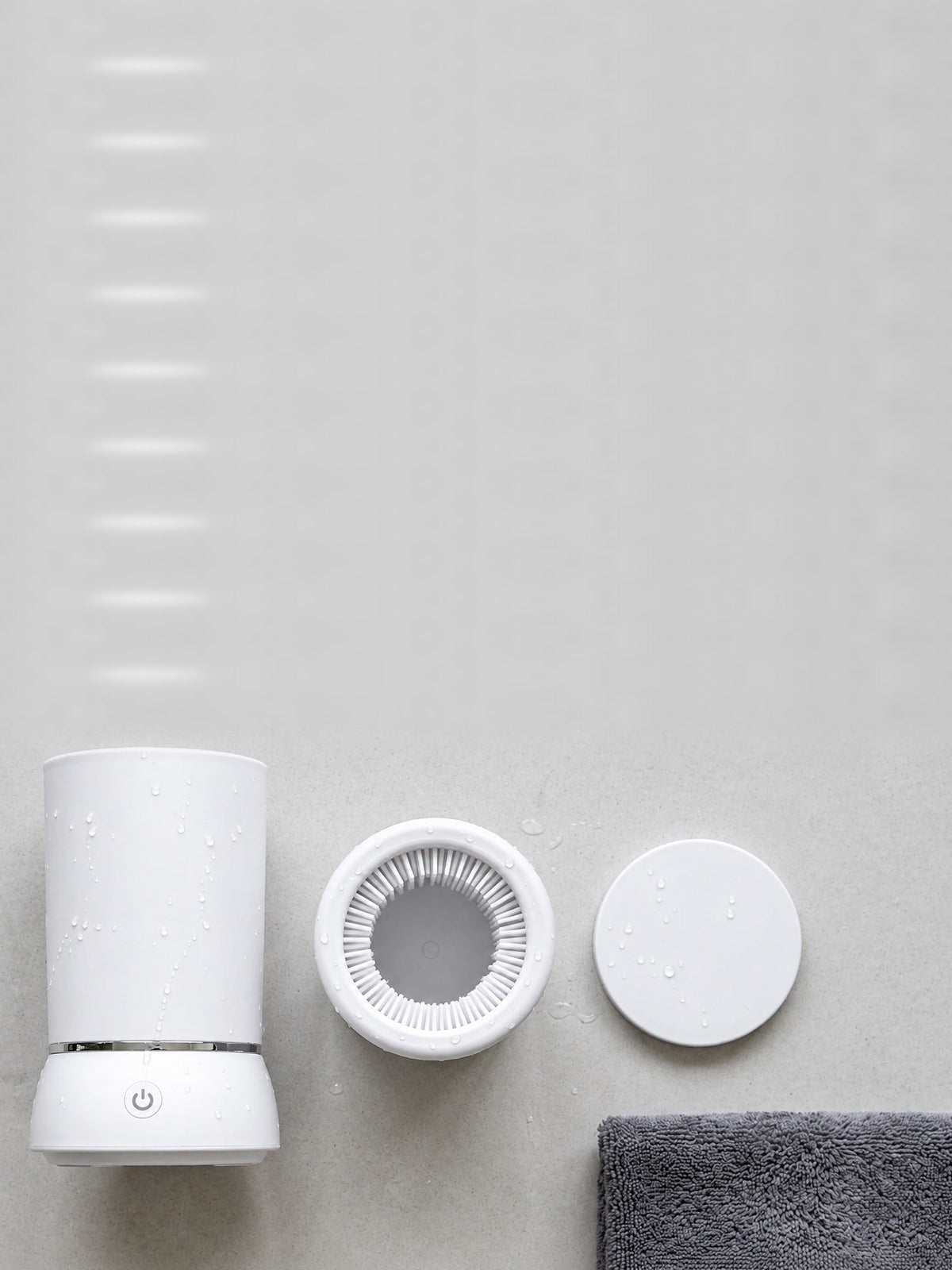 PawWash automatic paw cleaner in white, shown with the removable silicone brush insert and lid on a pale concrete surface